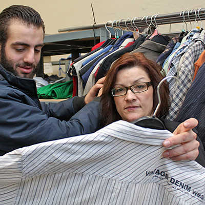 Die Leiterin der Kleiderkammer, Katja Kouts, und ihr Kunde Mohammed begutachten ein modisches Hemd.