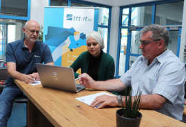 Simon (l.) und Rainer Schramm besprechen mit Alaa Jouri Ergebnisse einer Übungsaufgabe in der IT-Anwendungsentwicklung.