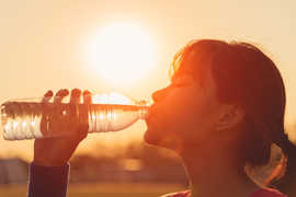 Der wichtigste Grundsatz bei großer Hitze lautet: Genügend trinken, am besten Wasser. Foto: FocusStocker - stock.adobe.com Eine Frau trinkt Wasser aus einer Flasche,