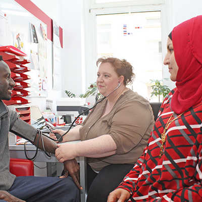 Krankenschwester Petra Classen und ihre Helferin Samah Mustapha messen Mohammad Fatana aus Zentralafrika in der Krankenstation den Blutdruck.
