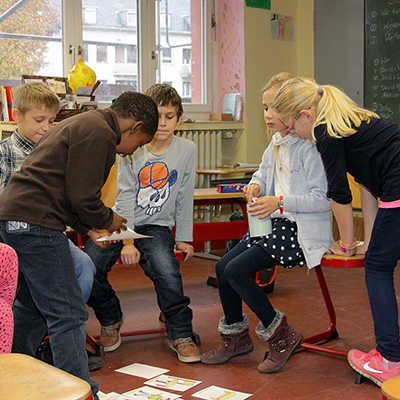 Passt das Kärtchen zur vorgelesenen Vokabel? Die Kinder des Deutschkurses lernen spielerisch Begriffe aus dem Schulalltag. 