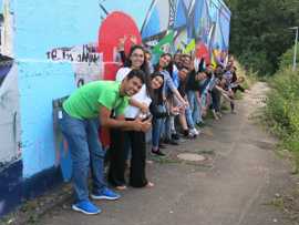 Die Jugendlichen und Organisatoren des Empowerment Workshops stehen vor dem Graffiti, das gemeinsam gestaltet wurde.