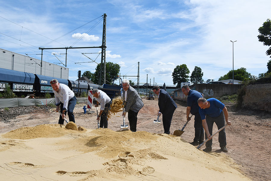 Baudezernent Andreas Ludwig (3. v. l.), ADD-Präsident Thomas Linnertz (3. v . r.), Ortsvorsteher Marc Borkam (r.) und die beteiligten Bauleiter greifen zur Schippe und geben das Startsignal für die neue Straße Überbrücken. 